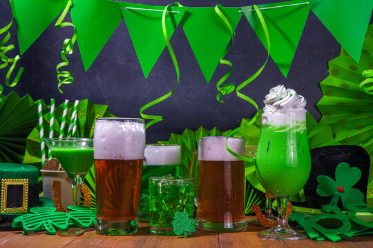 St Patrick's Day bar menu background. Set various golden, green beer glasses, different cocktails and drinks, with St. Patrick's Day party decor and accessories, on dark wooden background