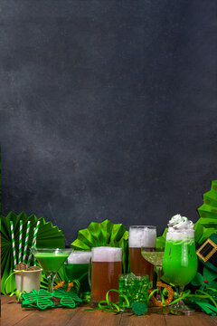 St Patrick's Day bar menu background. Set various golden, green beer glasses, different cocktails and drinks, with St. Patrick's Day party decor and accessories, on dark wooden background