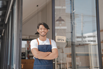 Young Asia coffee shop owner business man in apron with open sign at door shop.