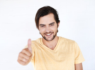Naklejka premium Thumbs up, winner and portrait of man in studio, white background or isolated emoji. Male model, thumb up and support of yes agreement, celebration and hand sign, vote or trust, thank you and success