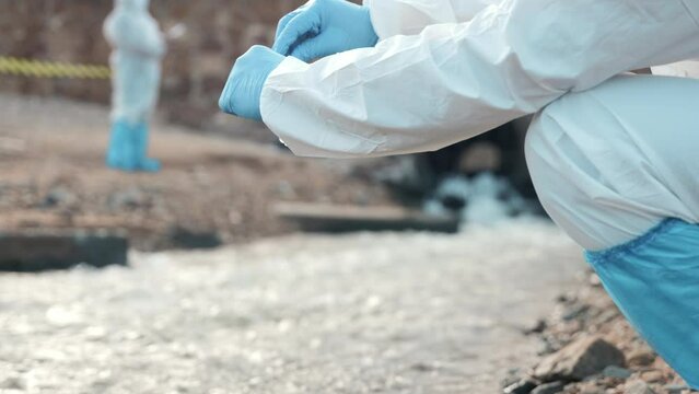 Ecologist sampling water from the river with test tube, Biologist wear protective suit and mask collects sample of waste water from industrial, problem environment, scientist environmentalist