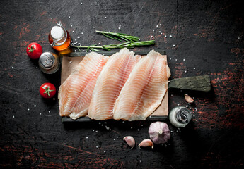 Fish fillet on a cutting Board with rosemary, garlic and spices. - 562100878