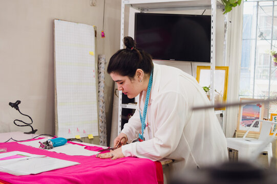 Busy young woman in her clothing design workshop, working on a prototype.
