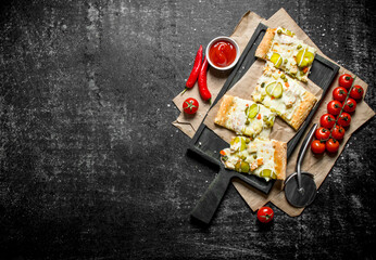 Slices of vegetable pizza with cherry tomatoes and sauce in bowl.