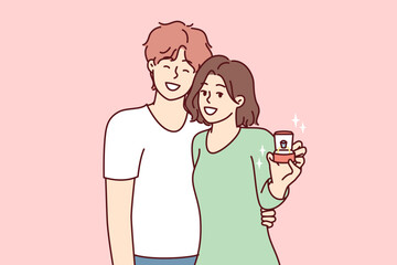 Young couple of man and woman stand in embrace and look at camera showing box with wedding ring. Bride and groom in casual clothes after proposal for joint family life. Flat vector illustration