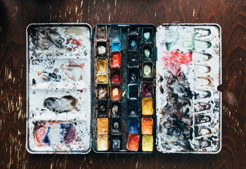 battered worn out watercolor palette, heavily used.
