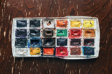battered worn out watercolor palette, heavily used.
