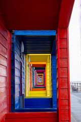 Fototapeta premium View Through The Porches Of Colourful Wooden Beach Huts At Saltburn-by-the-Sea On The North Yorkshire Coast On A Misty Day