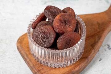 Dried apricots on stone background. Dark dried apricots in a glass bowl. Diet foods. close up