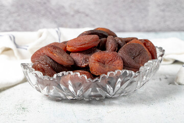 Dried apricots on stone background. Dark dried apricots in a glass bowl. Diet foods. close up
