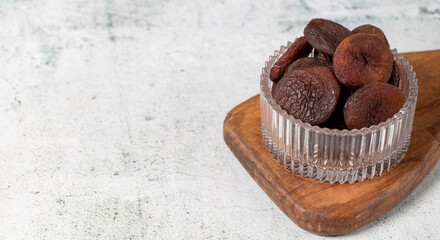 Dried apricots on stone background. Dark dried apricots in a glass bowl. Diet foods. close up