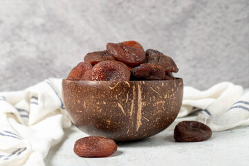 Dried apricots on stone background. Dark dried apricots in a glass bowl. Diet foods. close up