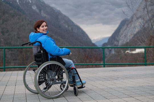 A woman in a wheelchair on a point view admires the high mountains. Thrust to life. 