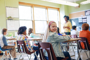 Obraz premium Classroom, children and education portrait of a girl writing to learn, study and gain knowledge. Diversity group students or kids in language class while learning for future, development and growth