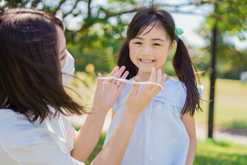 Obraz premium 子どもにマスクを付けさせるお母さん