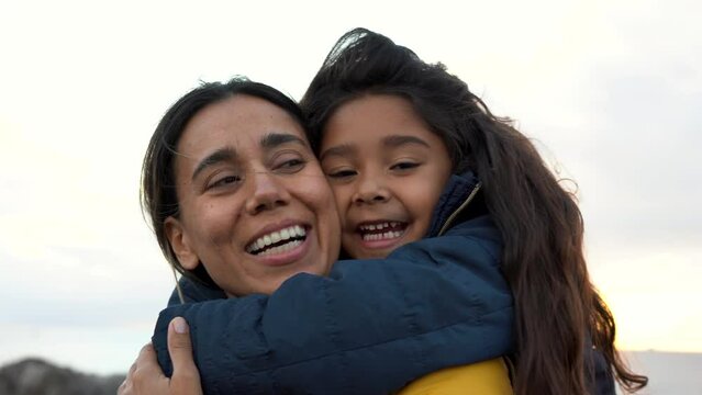 Happy latin mother and little daughter having fun together outdoor during winter tim