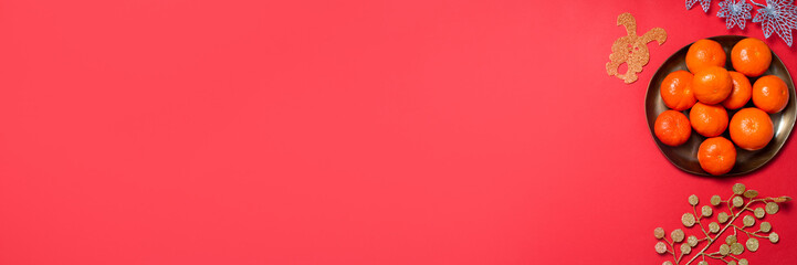 Chinese or lunar new year flat lay with plate of mandarins, paper rabbits as symbol of 2023 and flowers on red