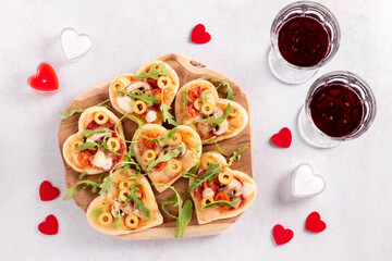 Fototapeta na wymiar Heart shape mini pizzas on wooden board for Valentines day holiday, top view