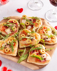 Heart shape mini pizzas on wooden board for Valentines day holiday, top view