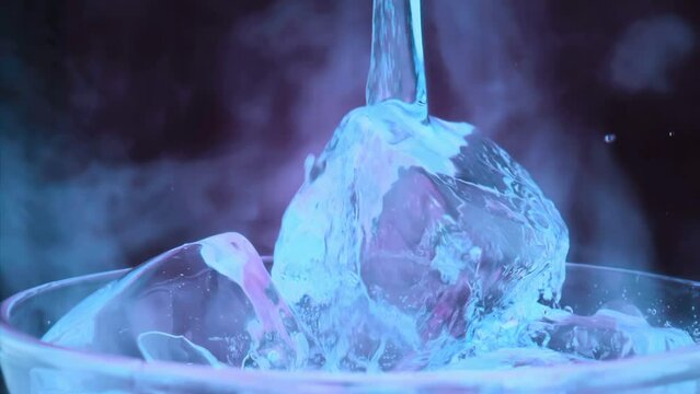 Slow motion 1000fps on pours blue cocktail on red ice cubes in rotate glass.Super slow motion pours blue cocktail on spin ice cubes in turn glass.Slow motion pours red ice cubes and alcohol cocktail