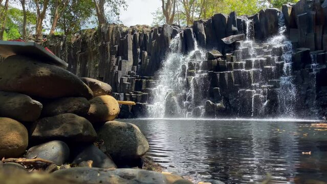 Falling water streams flow on black volcanic stone cascades in waterfall lake.  Rochester Falls waterfall - popular tourist spot in Savanne district in Mauritius.