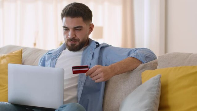 Online accountancy. Young middle eastern man entering credit card data on bank website on laptop, paying taxes from home