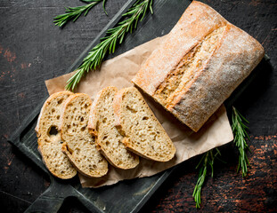 Sliced ciabatta bread on a cutting Board with rosemary.