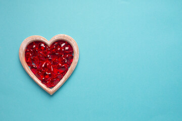 Wooden heart and red glass hearts on a blue background with copy space. Simple concept for Valentine's day holiday