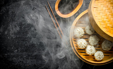 Hot dumplings manta in a bamboo steamer with soy sauce.