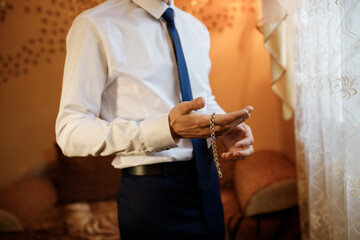 Businessman in white shirt putting bracelet on hand. Man fashion
