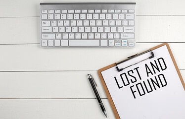 Home office workspace with keyboard, clipboard and pen with text LOST AND FOUND on white wooden background , business concept