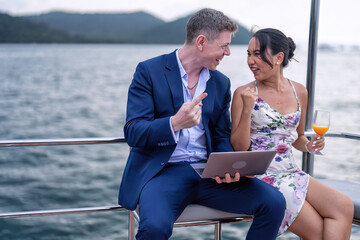 Business man and girl friend on holiday sailing on the yacht check laptop and get good news