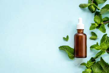 Green mint leaves with bottle of essential peppermint oil