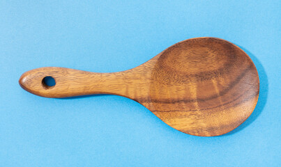 Wooden spoon isolated on blue background. Tropical wood