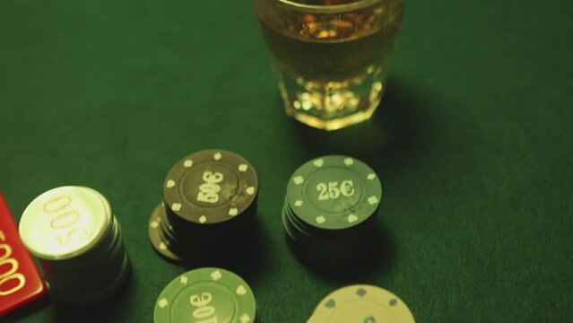 Poker chips are stacked on a green textured table smoke of cigars fills the room