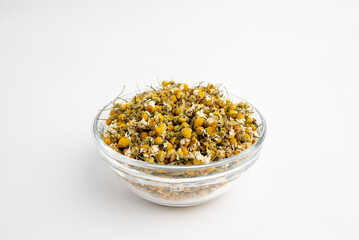 dried chamomile flowers in a glass dish on a white background