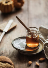 Honey background. Sweet honey on comb, glass jar with hazelnuts. On wooden background.