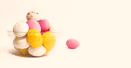 Colorful chocolate Easter eggs on beige background with copy space