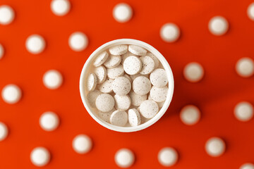 white dietary supplement pills top view on orange background. immune prevention care concept