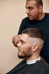 Fototapeta premium Barber shaving caucasian man in barber shop