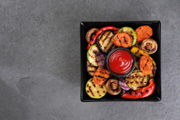 Grilled vegetables eggplants aubergine, carrots, zucchini, champignons, bell pepper, onion on a plate. Top view.