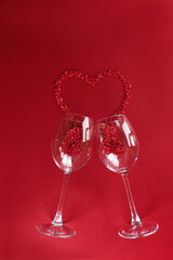 two wine glasses and small hearts on a red monochromatic background