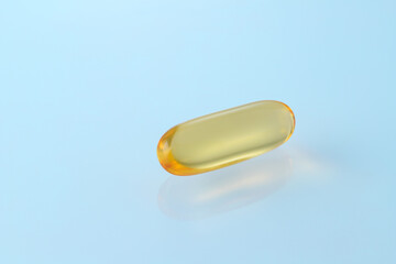 Omega 3 or fish oil capsule closeup on light blue background. Food supplement for healthy or cosmetic body care.