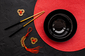 Golden chopsticks on black bowl with red napkin. Asian tabble place setting