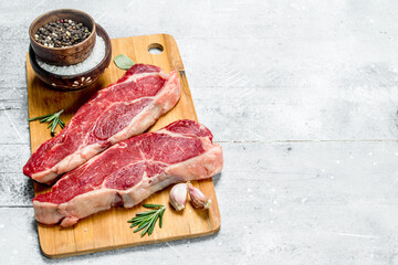 Raw beef steaks with spices and herbs.