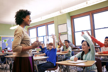 School, teacher and children raise their hands to ask or answer an academic question for learning. Diversity, education and primary school kids speaking to their woman educator in the classroom. - obrazy, fototapety, plakaty