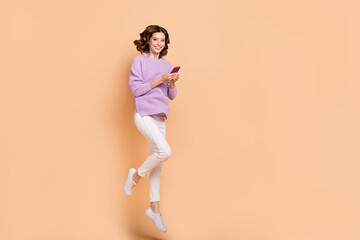 Fototapeta na wymiar Full length photo of adorable lovely lady wear purple trendy outfit bought use modern device empty space isolated on beige color background