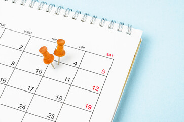 The Embroidered wooden pins on a blank calendar on the Friday 11th with selective focus on blue background.