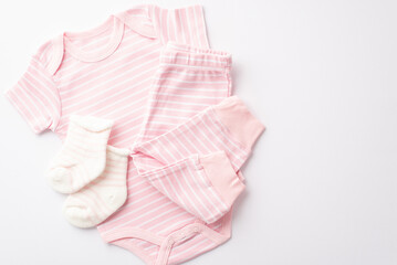 Infant clothing concept. Top view photo of pink bodysuit pants and socks on isolated white background