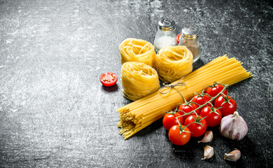 Spaghetti and tagliatelle raw with garlic cloves and tomatoes.